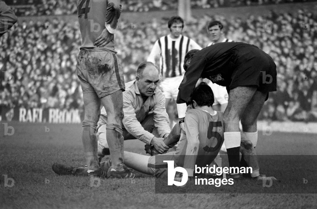 English League Division One match at the HawthornsWest Bromwich Albion 3 v Sheffield Wednesday 0. Colin Prophett of Sheffield Wednesday receives attention for an injured leg from trainer and referee. November 1969 (photo)