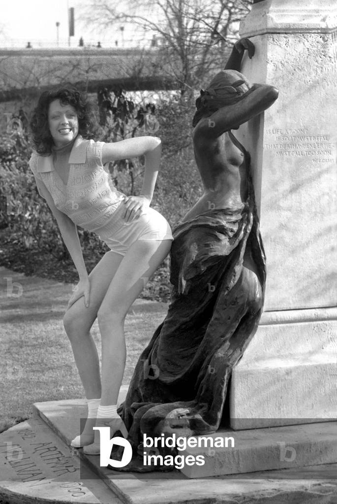 Fashion scene from Woolworth's. Woman standing next to a sculpture in the park wearing short sleeved top 
February 1975