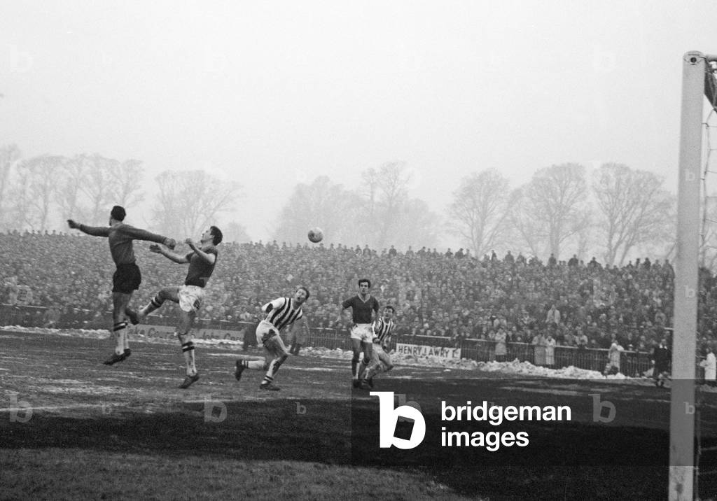 English FA Cup Third Round match. Plymouth Argyle 1 v West Bromwich Albion 5. Argyle goalkeeper Dave MacLaren jumps up with his defender Gordon Fincham to clear the ball away from West Brom's Derek Kevan. Looking on is Plymouth defender Mike Reeves. 5th January 1963 (photo)