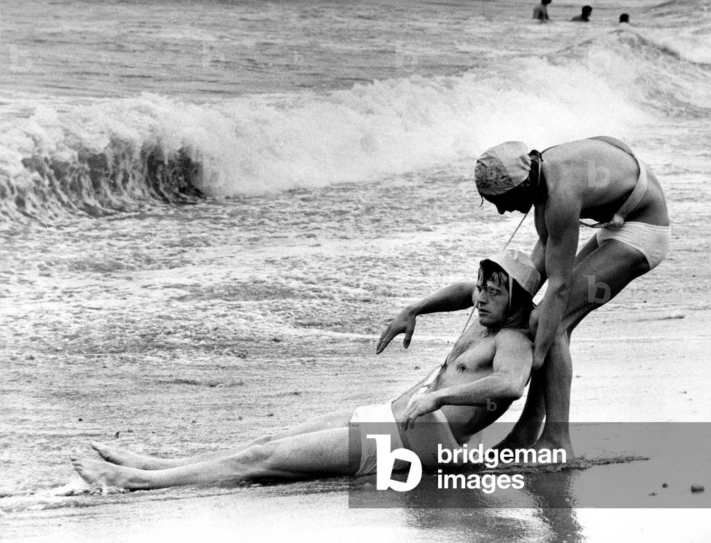 Two Competitors in the heats of the Nation Lifeguard Championship held on the South Foreshore, at South Shields reach the shore during a mock rescue from the icy North Sea, August 1972 (b/w photo)