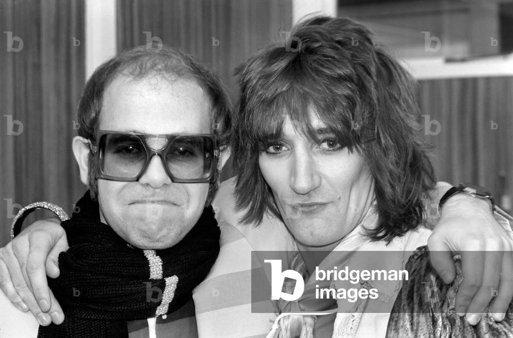 Rod Stewart and Elton John. Pop superstars Rod Stewart and Elton John make it up back stage at the Olympic tonight just before Rod went on stage for the third night of his series of London concerts, December 1976 (b/w photo)