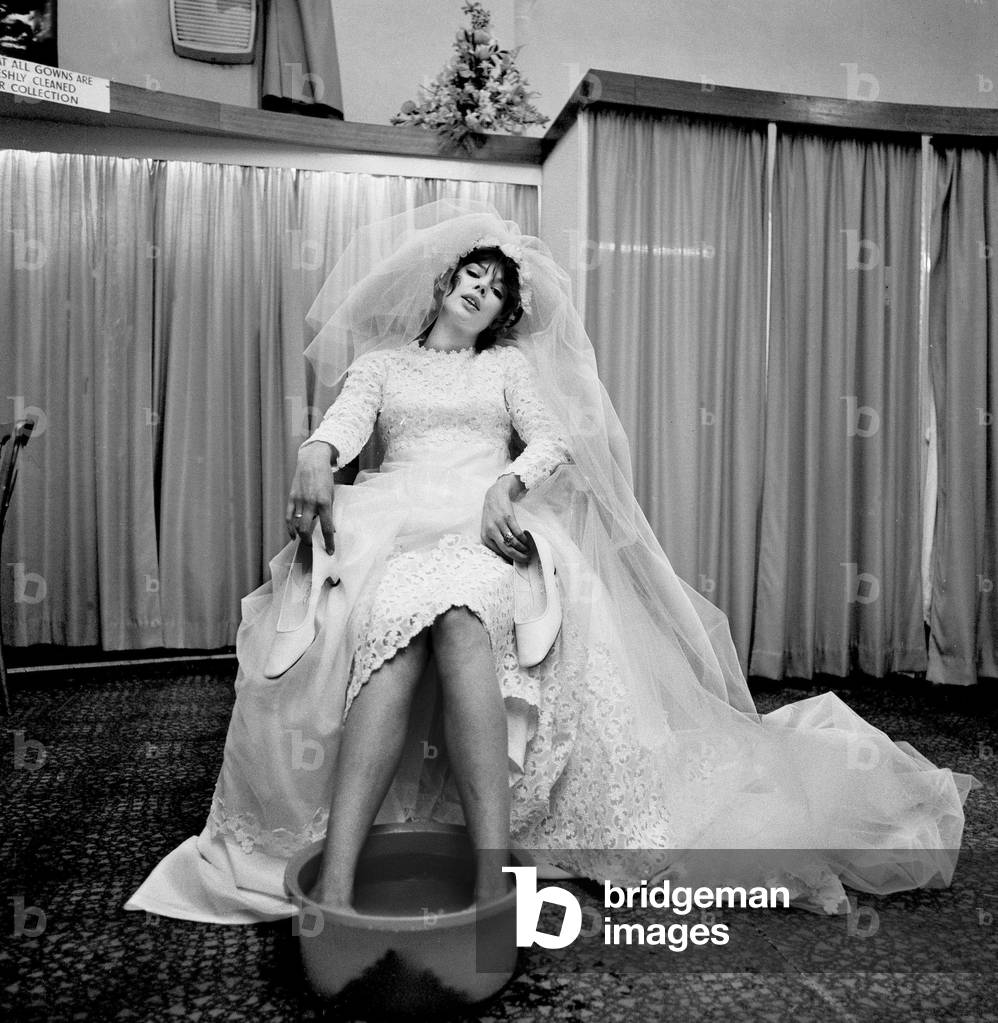 The thing that every bride must long to do at the end of her greatest, happiest, but tiring day is to relax with her feet in a nice bowl of warm water, just like our model bride pictured here , 8th April 1970 (b/w photo)