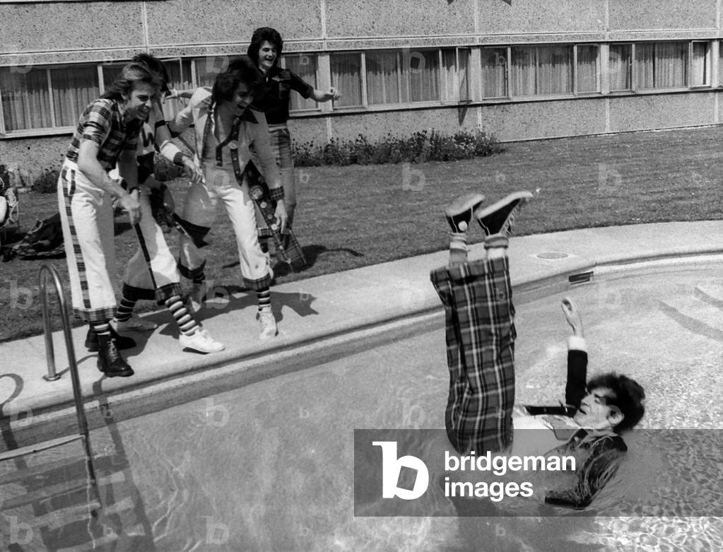 Bay City Rollers guitarist Alan Longmuir is thrown into the swimming pool by other band members, 1975.