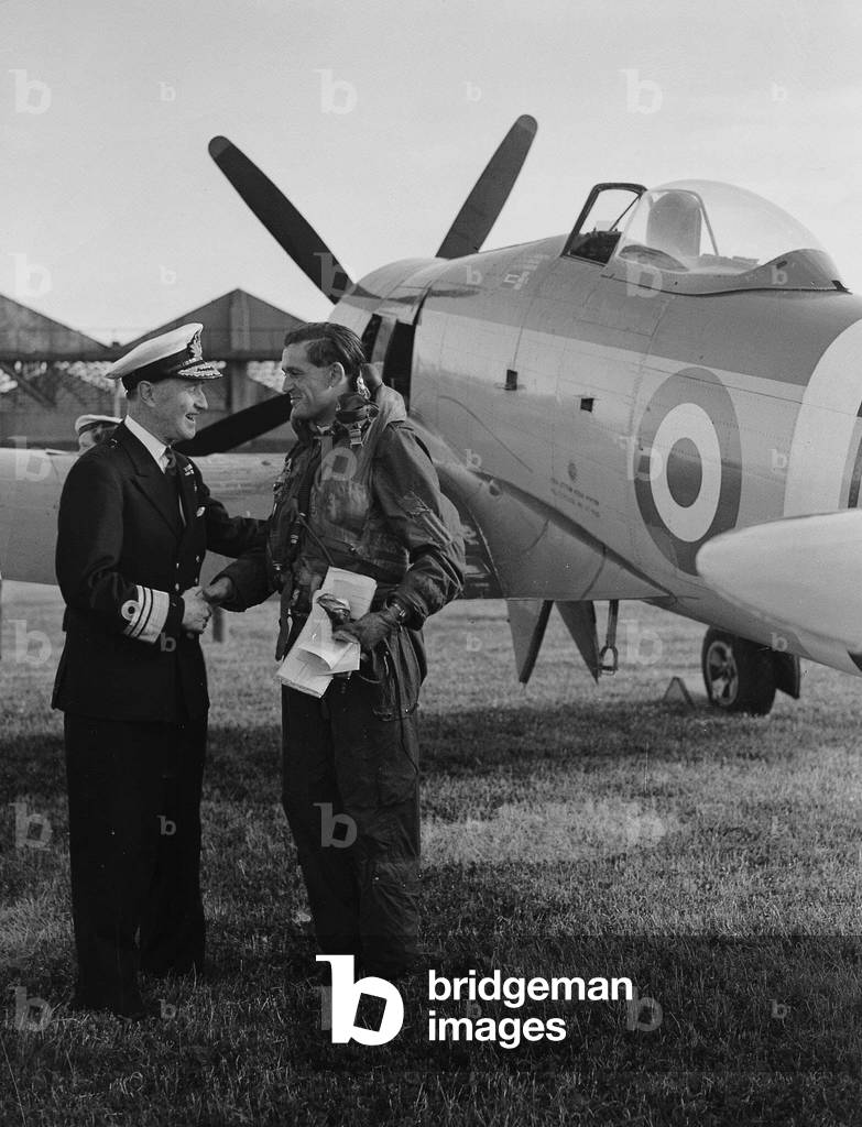 A Fleet Air Arm Pilot standing beside his Hawker Sea Fury aircraft is welcomed home with a handshake by his Commander, May 1951 (b/w photo)