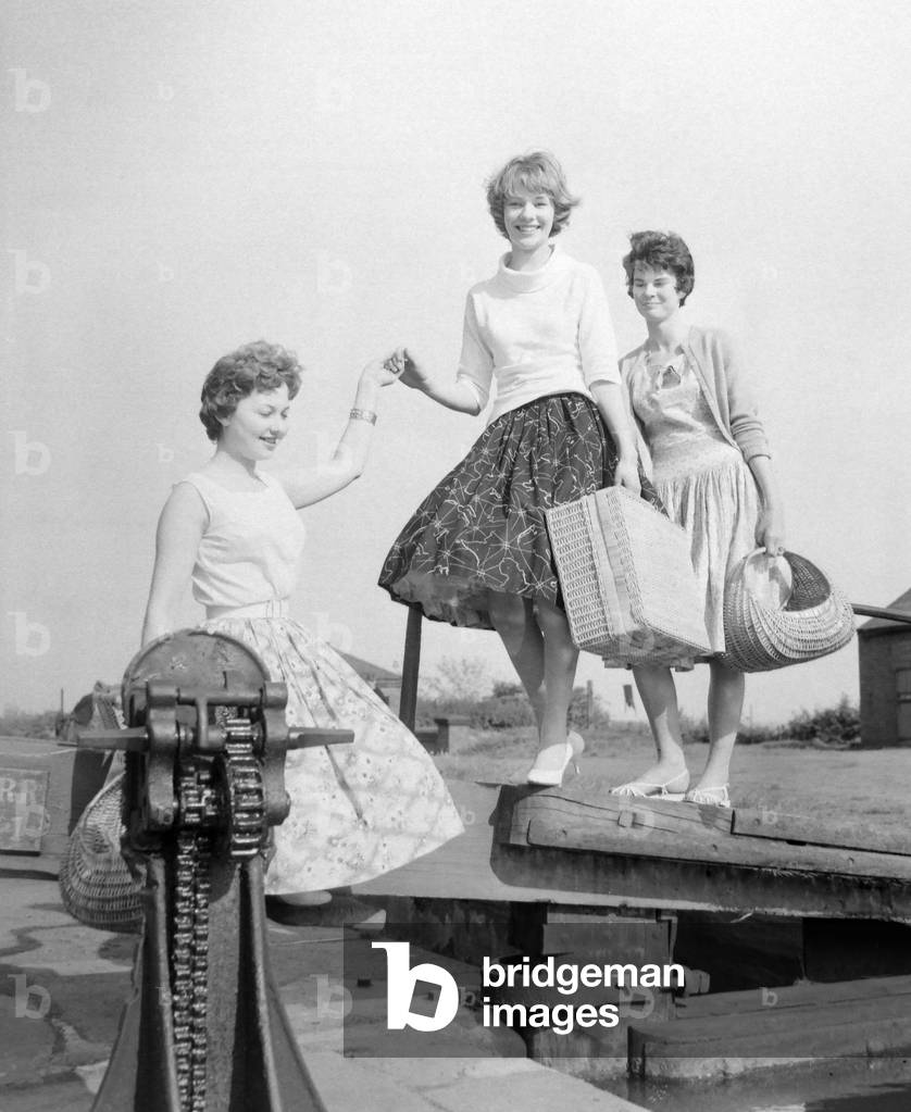 Three girls preparing for a picnic along the side of the canal at Perry Barr. They are Ann Rowland, Mary Russell and Anne Hill. May 1959