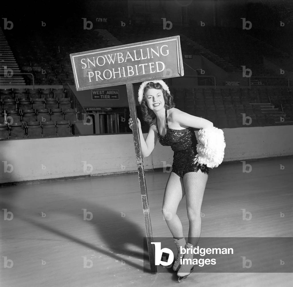 Ice skater with snow balling prohibited sign, 1959 (b/w photo)