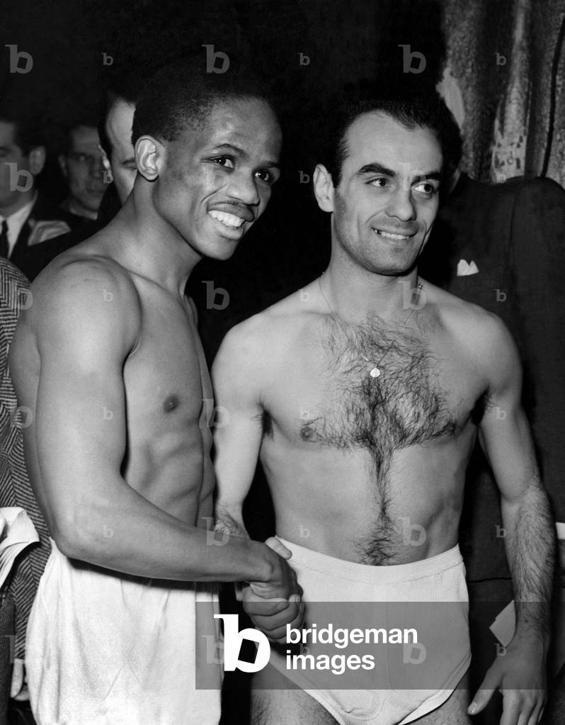 Jake Tuli (former Empire Flyweight Champion) on left and Nazzarena Gianelli (Italy) weigh-in at Jack Solomons' Headquarters in Gt. Windmill Street, London, for their bout at Harringay Arena Tonight. December 1954