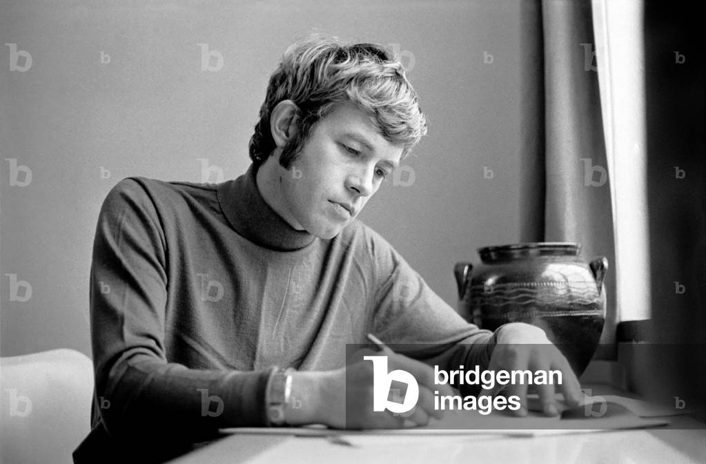 Families: Mother, father and children. Man relaxing at home, reading a book on his sofa, writing at table. November 1969