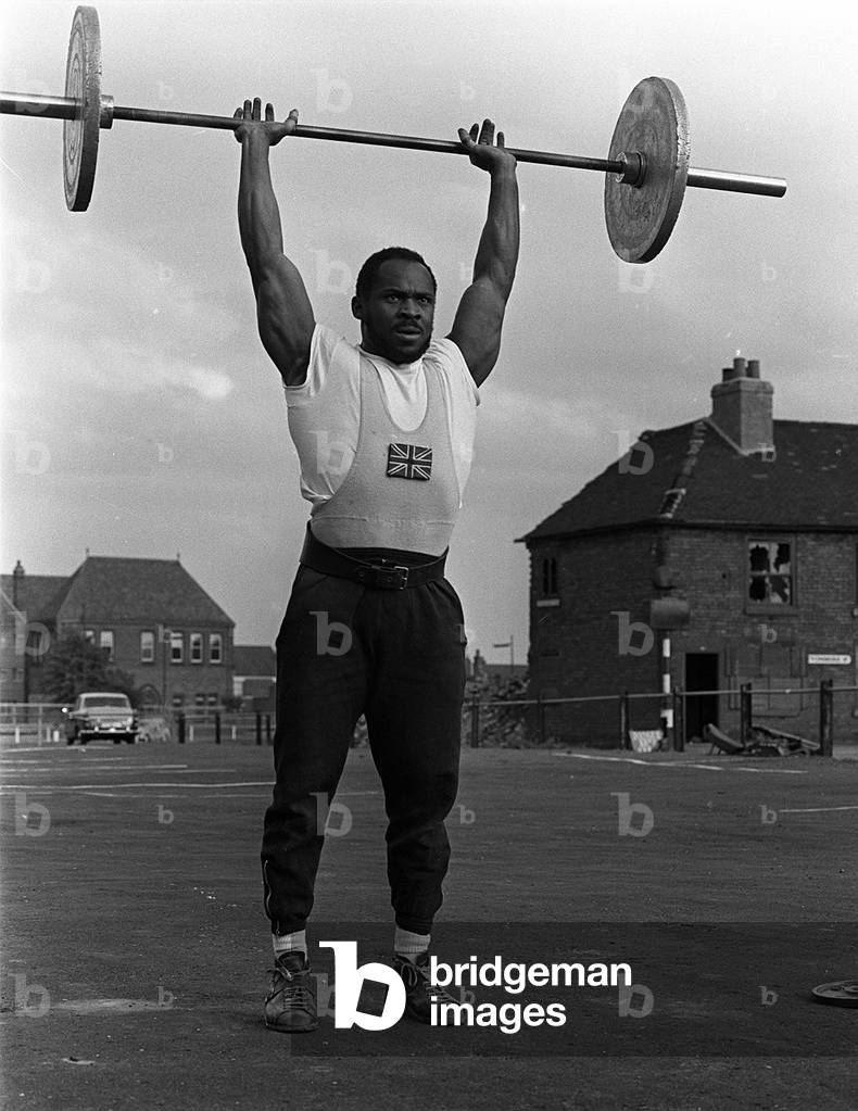 Weightlifter Louis Martin training in Rawdon street where he lives in Derby, 1965 (b/w photo)