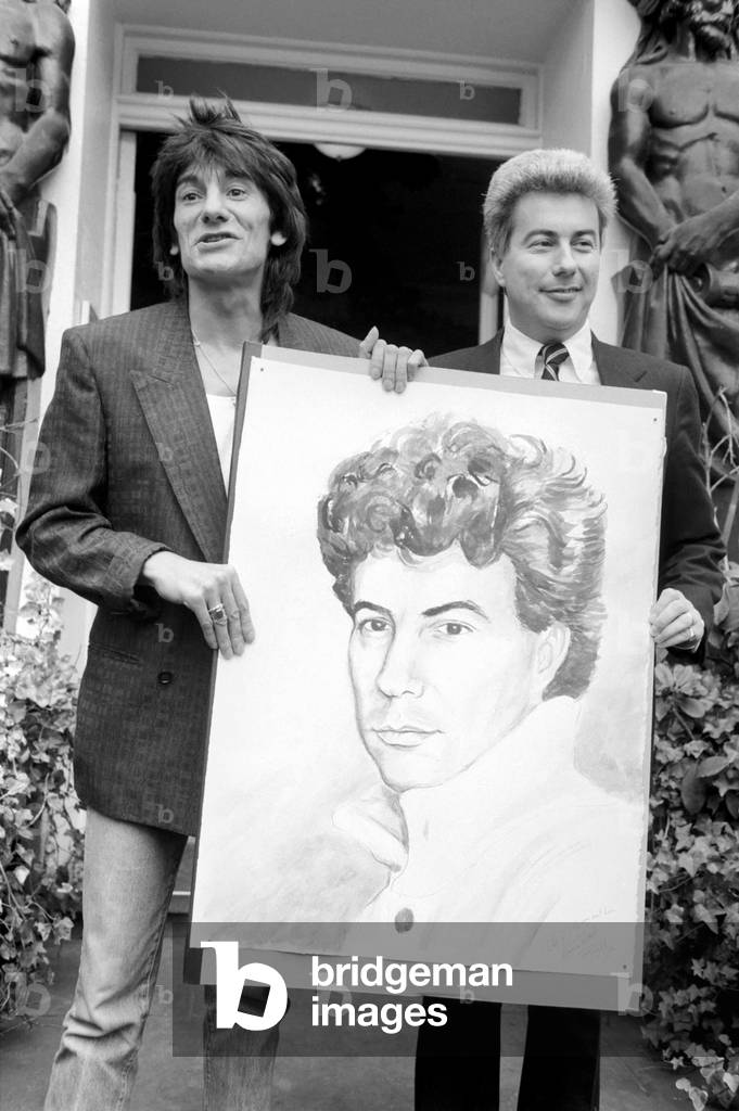 Rolling Stones: Ronnie Wood holds a painting of author Ken Follett who stands next to him. September 1987