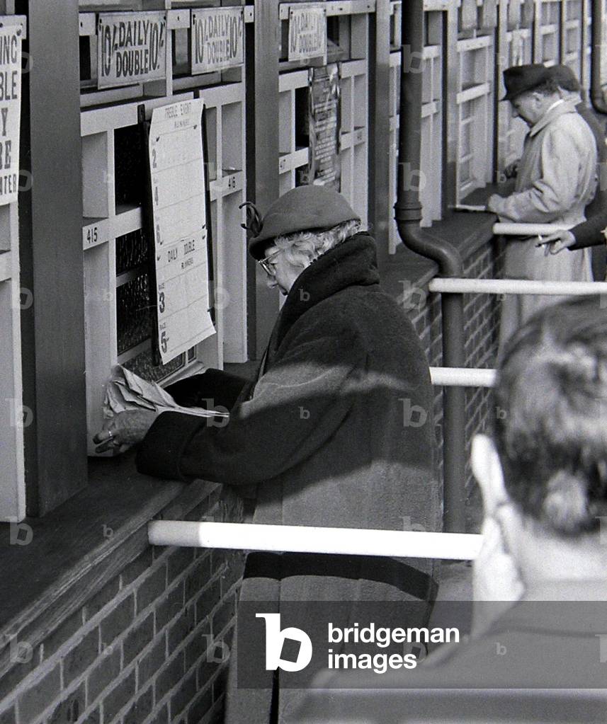 An elderly woman placing her bet at the tote before a race
March 1963
