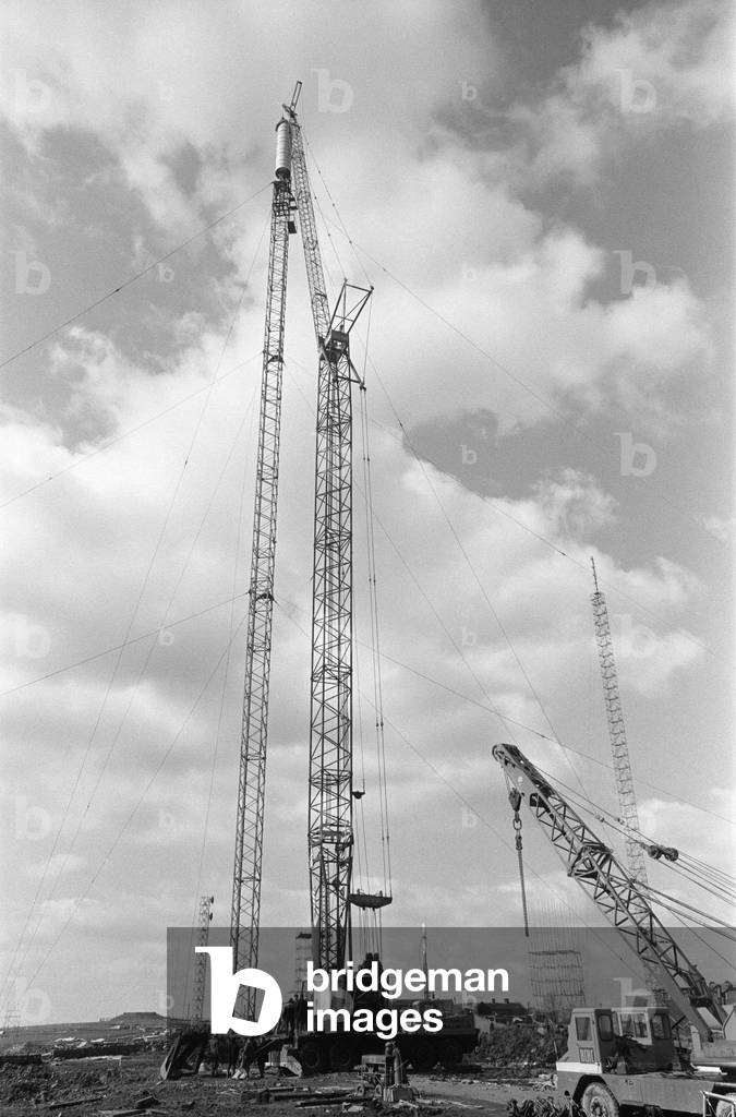 The collapsed Emley Moor transmitting station mast lies on the ground as engineers put the finishing touches to the BBC Two mast which towers 307ft off the ground. 16th April 1969 (b/w photo)
