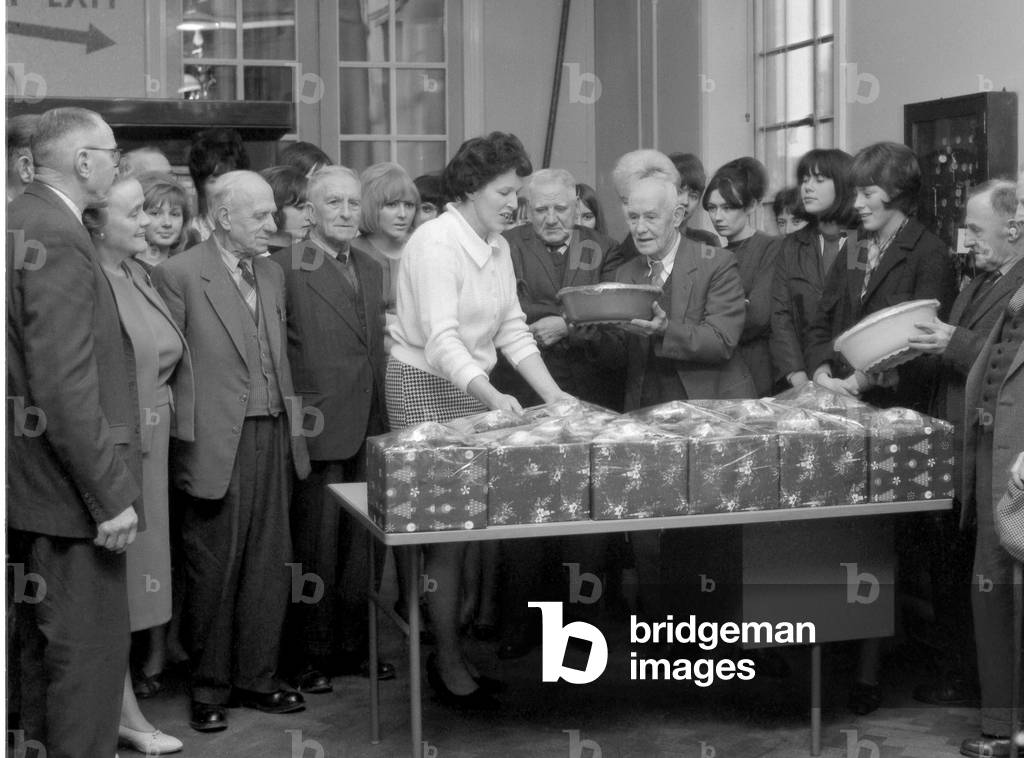 Coventry telephonists presenting Christmas parcels to residents of Bond's Hospital almshouses in Hill Street and retired Post Office employees at Coventry Telephone Exchange at Greyfriars Lane, Coventry. 21st December 1965 (b/w photo)