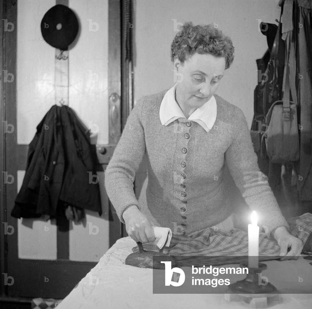 Mrs Dorothy Mead who still lights her house with gas lamps.
Seen here ironing by candle light
Circa 1958