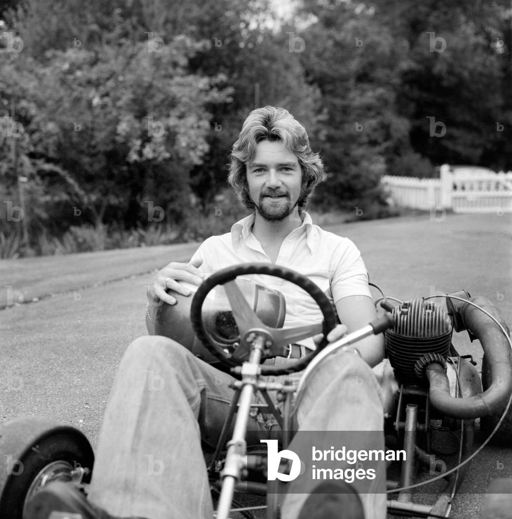 Noel Edmonds at home relaxing in the garden riding a go kart, September 1976 (b/w photo)