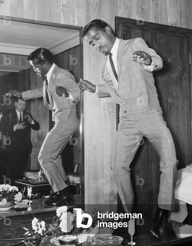 American singer Sammy Davis Junior performs a dance on a cocktail table at the Mayfair Hotel in London. 3rd May 1966 (b/w photo)