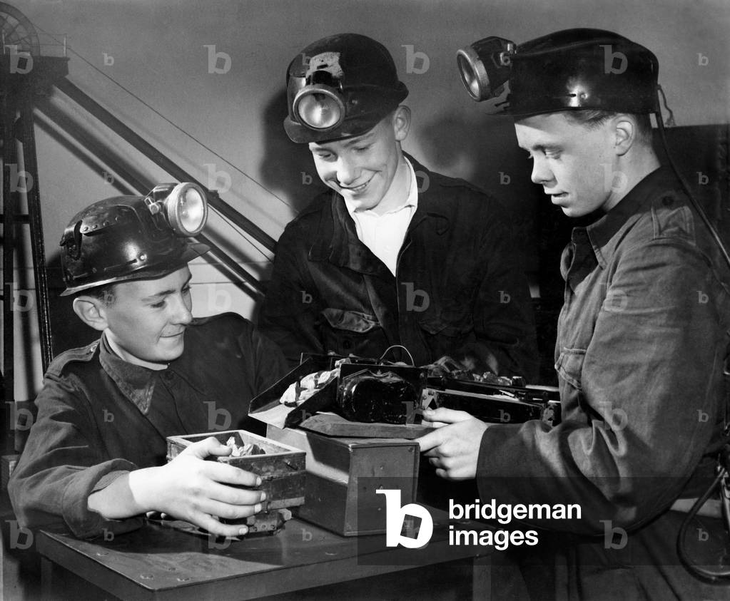Boy trainees take a 16 week course at the Colliery school before starting work in the pit. Arthur Clough, 15, George Davison, 17, and Peter Brown, 15, learn how a coal conveyor works from a model. Boys get free lunches and time off during the morning to drink a free half pint of milk. 
July 1954