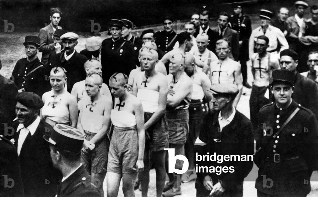 World War II: French men and women, accused of collaborating with the Germans during the occupation are marched through the streets of Paris in the early days of the liberation. They have had their heads shaven and are partially stripped. February 1945