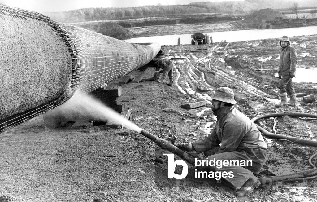 A workman sprays on the gas pipelines concrete coat in December 1974