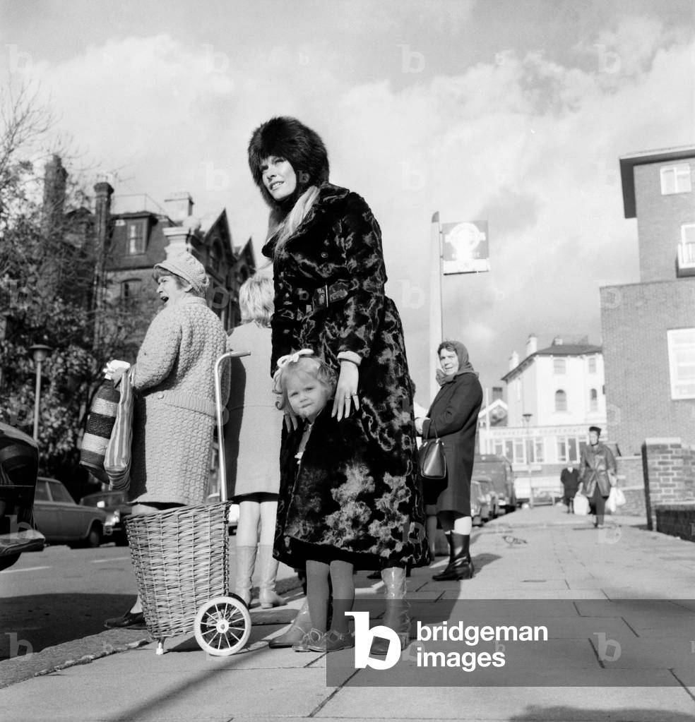 actress Francis Dean who lives in Fairfax Road, N.W.6., wears a maxi-coat and it is made of synthetic fur by astraka. She was out today with daughter Belinda (2) and Belinda found maxis very cosy indeed especially with today's weather. They were waiting for a No. 31 bus where the pictures were taken. November 1969
