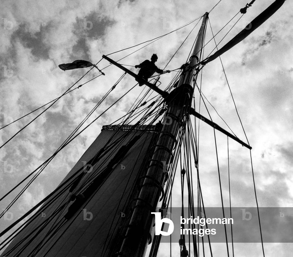 S. L. C. Latham, aged 17, astride the cross tree helping to send up the top mast aboard the school of navigation 103 ton seagoing training vessel Moyana in the Solent, Southampton, 28th May 1948 (b/w photo)