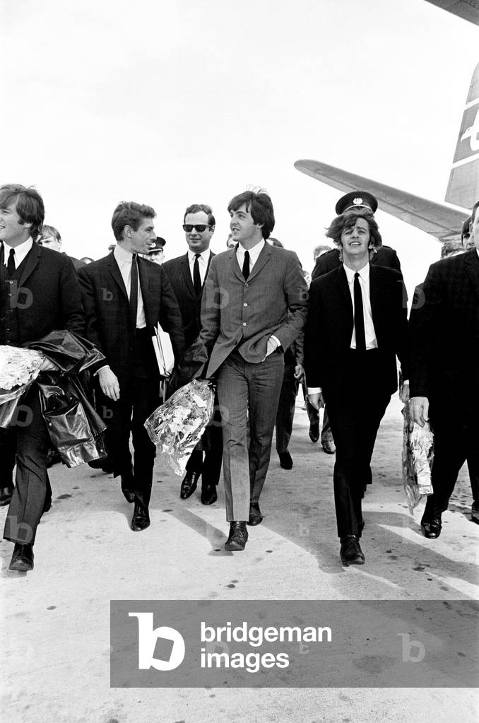 The Beatles in Liverpool for the Premier of a Hard Day's Night. John Lennon, George Harrison and Paul McCartney pictured here with flowers given to the by fans, as they walk along the concourse after leaving the place at a Liverpool airport. 10th July 1964.