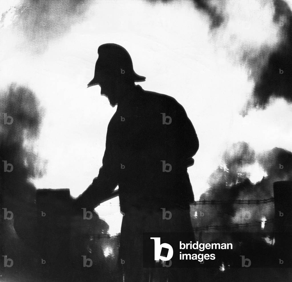 A silhouette of fireman fighting the blaze, 1970