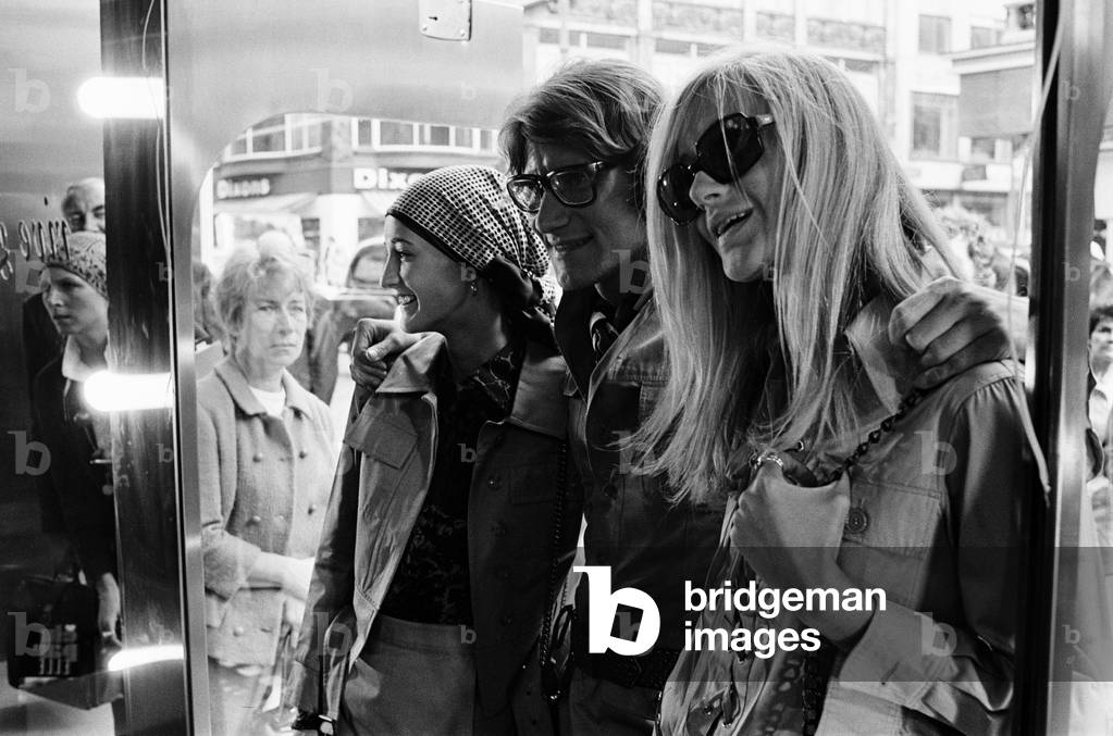 Yves Saint Laurent, designer pictured outside his first London Rive Gauche store on New Bond Street, London, opening day of boutique, and with muses Louise de La Falaise, aka Loulou (left) and Betty Catroux (right). 10th September 1969 (b/w photo)