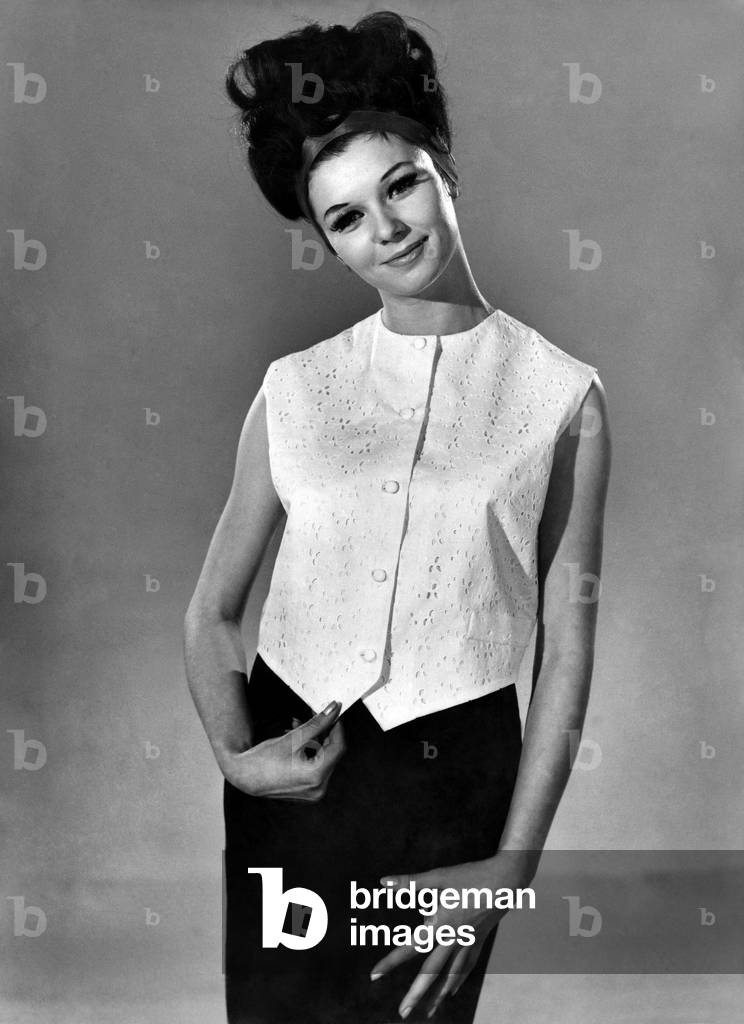 Model Merriel Weston wearing a sleeveless blouse top and black skirt, August 1963 (b/w photo)