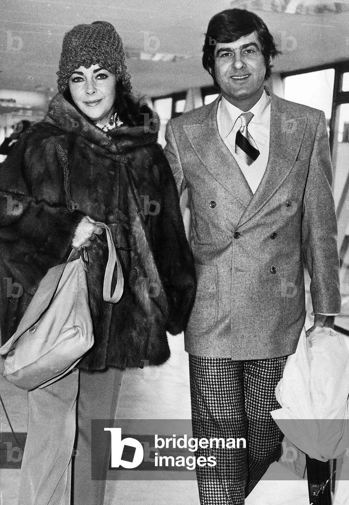 Elizabeth Taylor with boyfriend Henry Wynberg at Heathrow about to board a plane to Los Angeles, November 1973 (b/w photo)