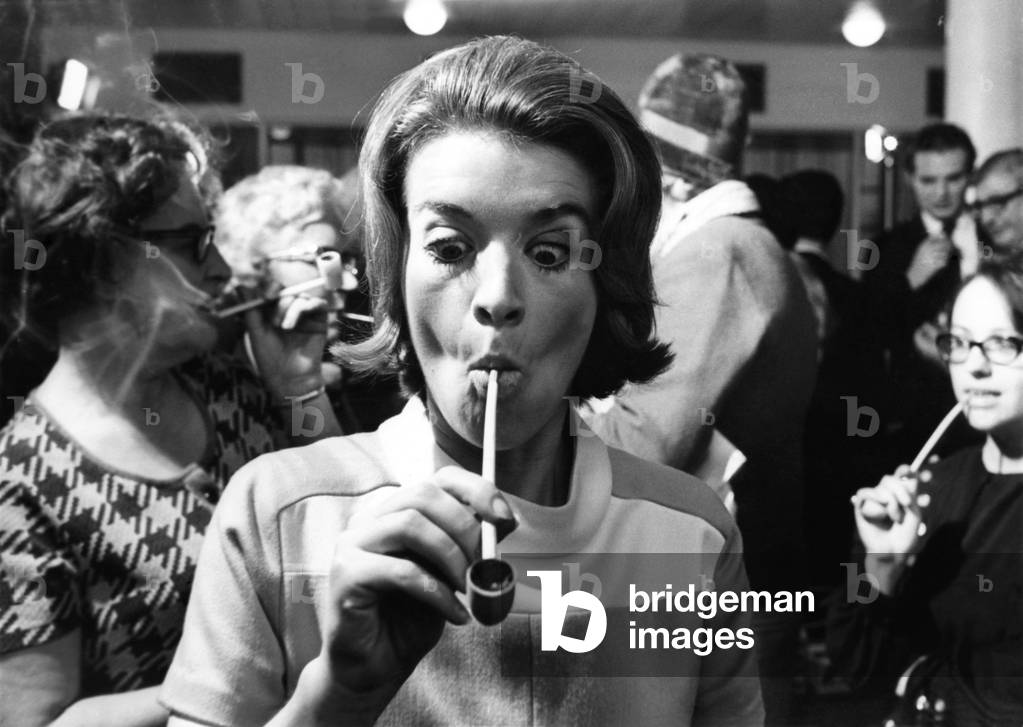 Blonde 28-year-old Jane Lumby experiments with her first pipe smoke at the Festival Hall - she doesn't look too happy with the clay pipe that she tried. October 1969