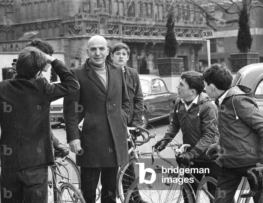 Actor Savalas Telly, surronded by young fans with bikes, during a walk in London with his wife.
Kojak
February 1968