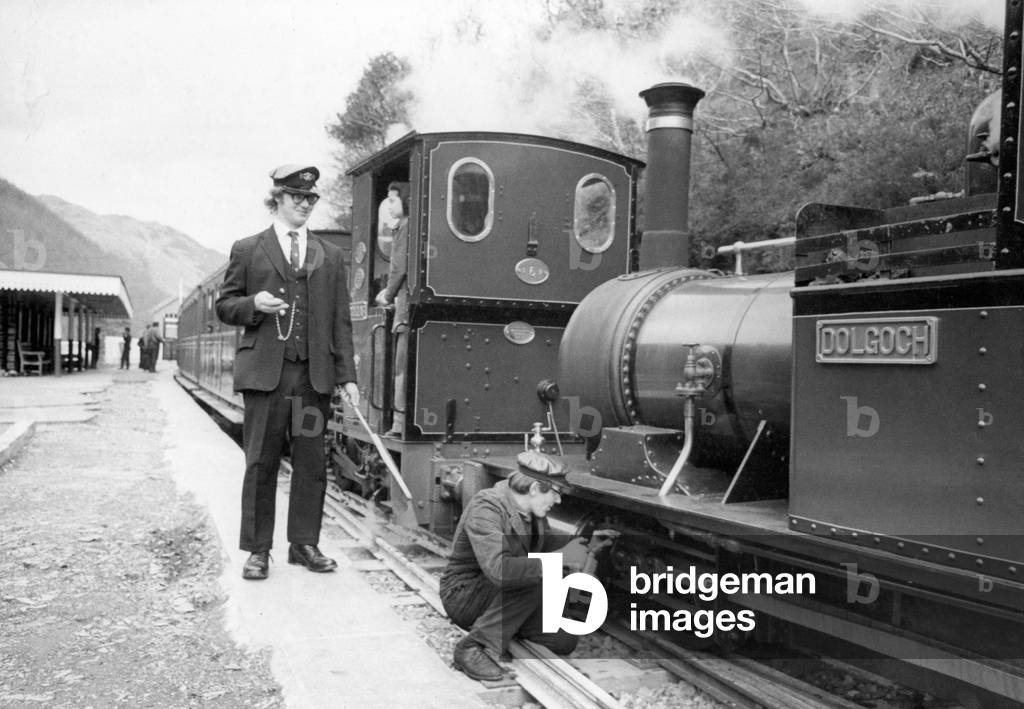 A woker applying some oil to one of the steam trains on the Talyllyn railway line which runs for 7.25 miles from Tywyn on the Mid-Wales coast to Nant Gwernol near the village of Abergynolwyn. 22nd April 1976 (b/w photo)