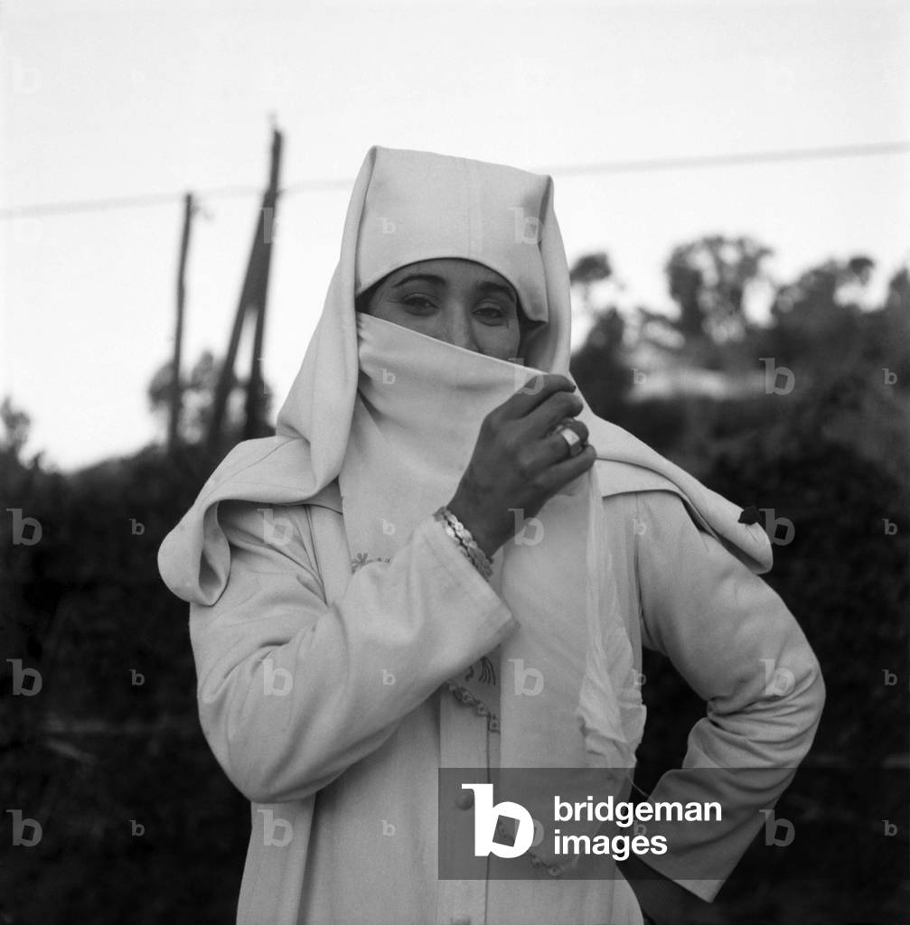Woman putting on a Djellabah traditional dress. January 1953 D216-015