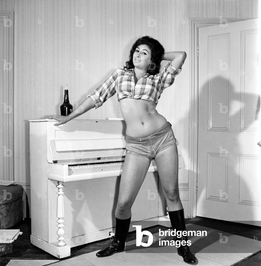 Large chested Denise Crooke seen here banging out a tune on the piano, 1965 (b/w photo)