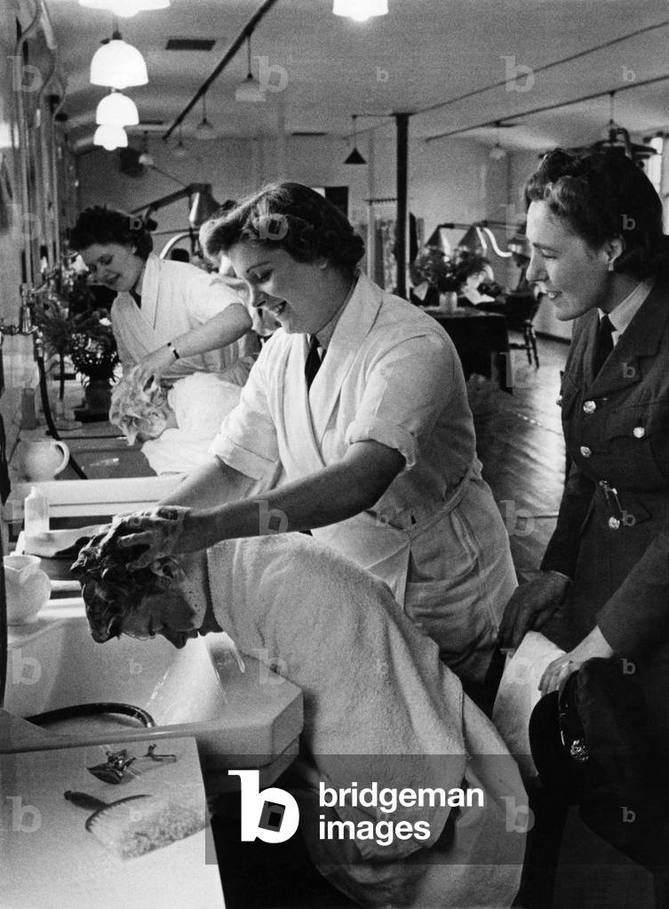 World War II Women. W.A.A.F. hairdresser seen here shampooing (washing) new recruits hair. September 1942