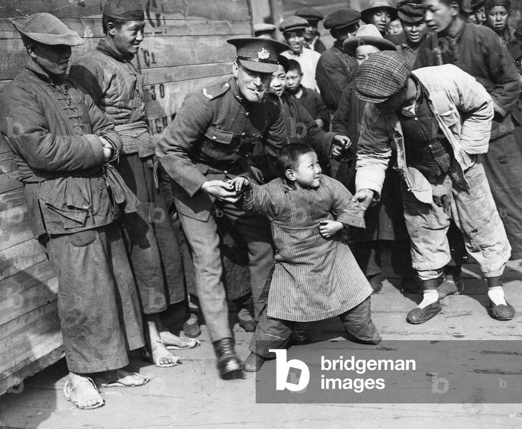 A young Chinese boy is not sure that he wants to play with the newly arrived soldier of the 2nd Gloucester's, Shanghai March 1927 (b/w photo)