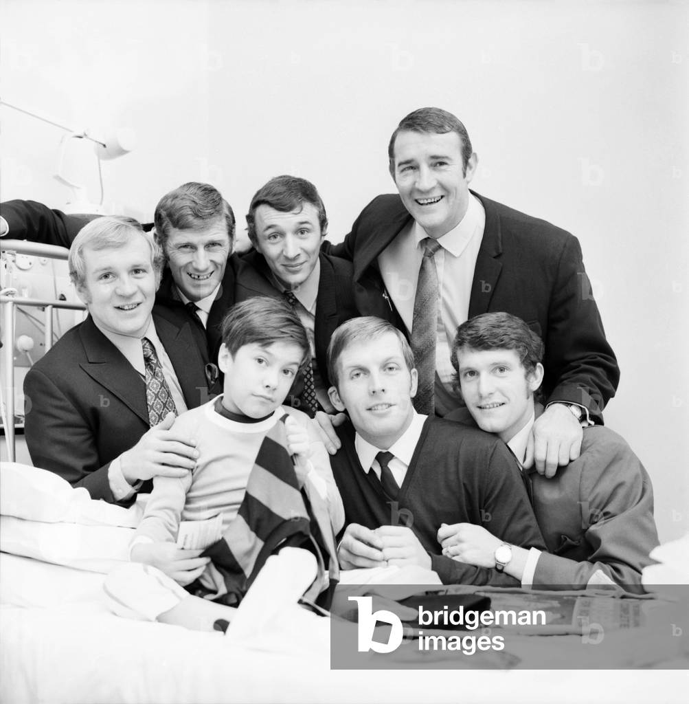 15 year old Nigel Shadbolt of Chipping Campden Gloucs. , who is in St. Mary's hospital, Paddington awaiting a kidney transplant was visited today by 6 of his heroes. Members of the Manchester city football team, who prior to playing and beating West Ham at Upton park arrived at the hospital with playing kit and pictures for Nigel. Nigel surrounded by his heroes L-R: Francis Lee, Tony Book, Mike Summerbee, coach Malcolm Allison, Oakes, and Doyle. December 1969 (photo)