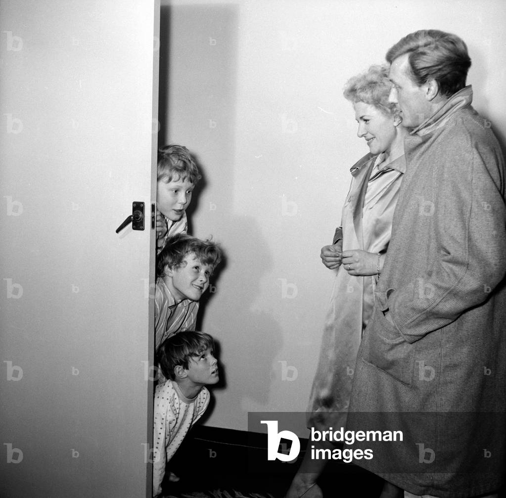 British singer and actor Gary Miller with his wife Joy wave goodbye to their children, Jonty Pip and Kit, as they go out for the evening, leaving Marjorie Proops babysitting them, 13th April 1960 (b/w photo)