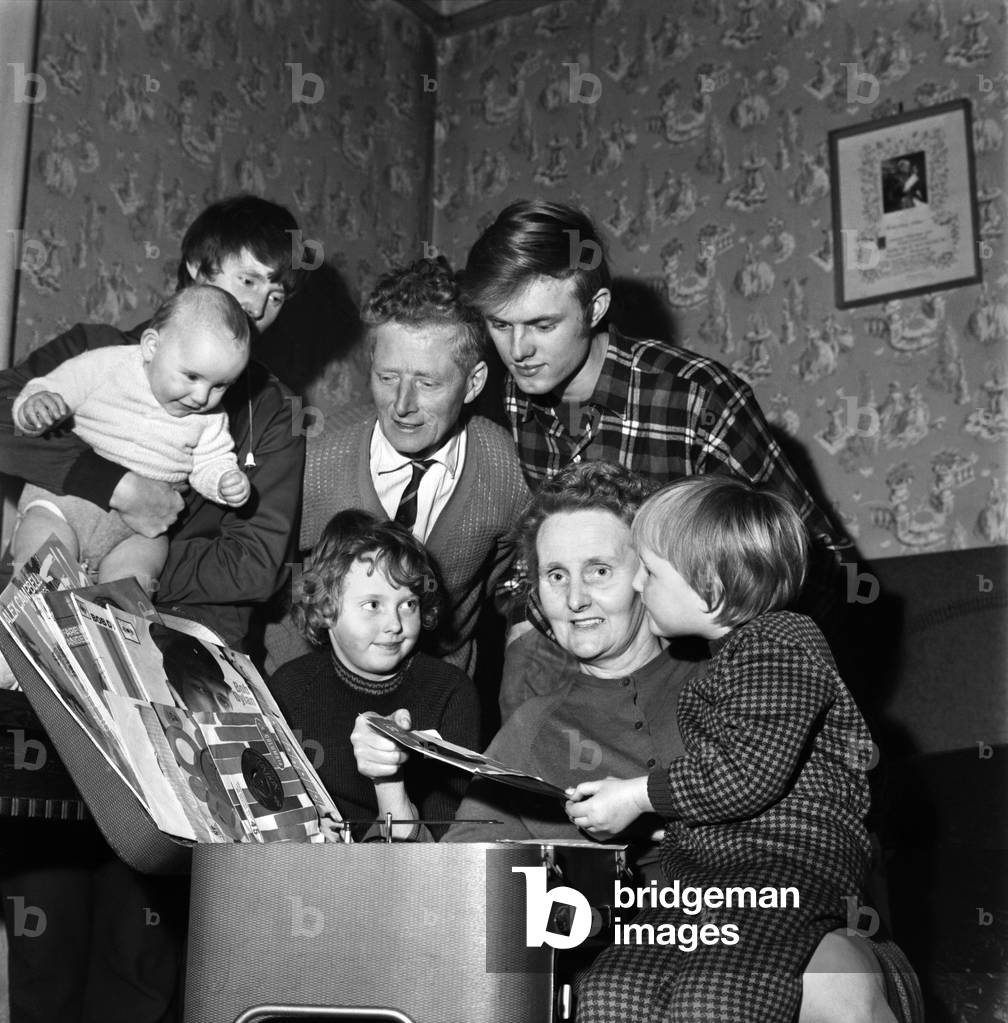Pulling out vinyl records at her Acton Terrace home in Wigan is Mrs. Rose Sharkey watched by her husband Lawrence, son Kevin and daughter Christine aged 7. December 1969