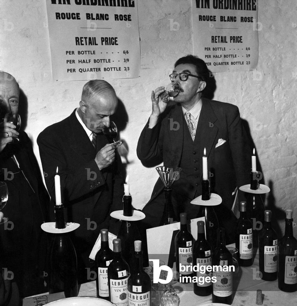 Henri De Villaine, owner of the Domain de la Romance Conti, near the village of Vosne-Romance, Burgundy, samples wines at the annual tasting of French wines held at the cellars of J.T.P. Tebegue & Co., Ltd. 
October 1953