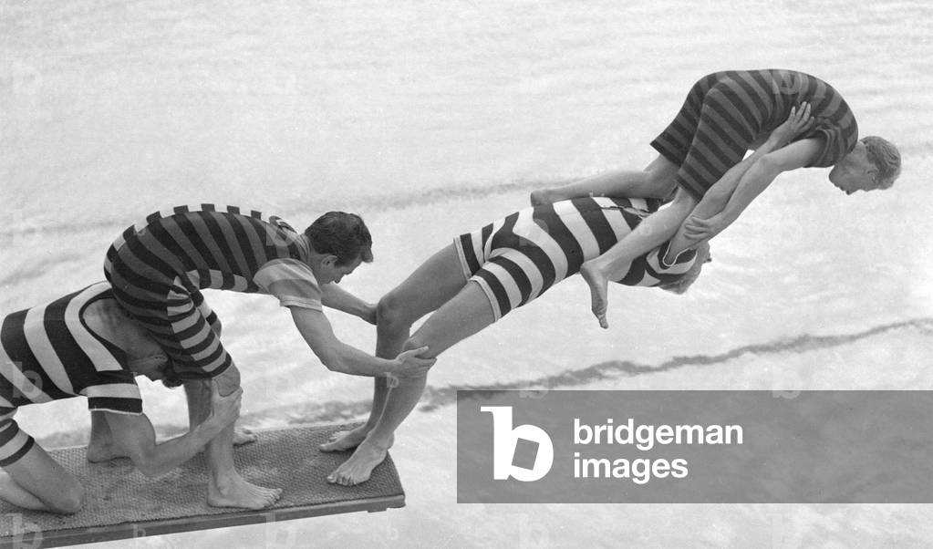 Acrobats from the Leon Marco Water Show clown about on a diving board, c.1935 (b/w photo)