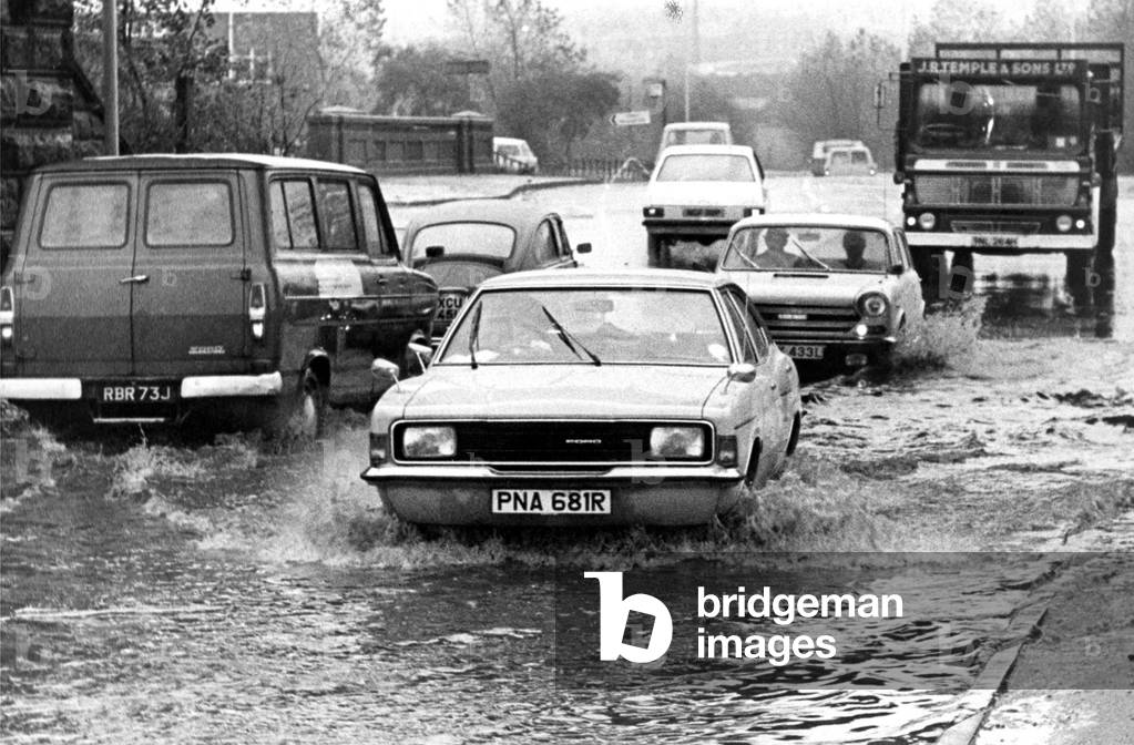 Traffic negotiates floodwater on Team Valley Trading Estate, Gateshead in 1976 (b/w photo)