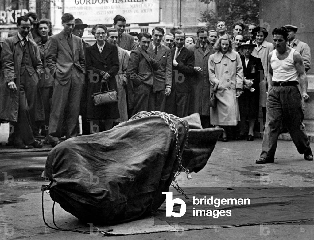 Streets Entertainment. A escapologist attempts to escape from his chains and sack in a London street. October 1948