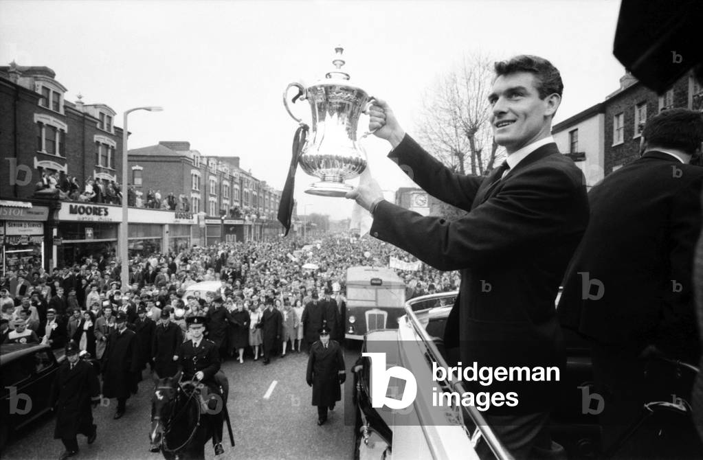Tottenham Hotspur team hold the FA Cup trophy aloft from an open top double decker bus to a crowd of fans as they arrive home after defeating Burnley 3-1 in the FA Cup Final at Wembley. May 1962 Q3890-002 (photo)
