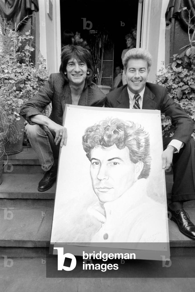 Rolling Stones: Ronnie Wood holds a painting of author Ken Follett who stands next to him. September 1987