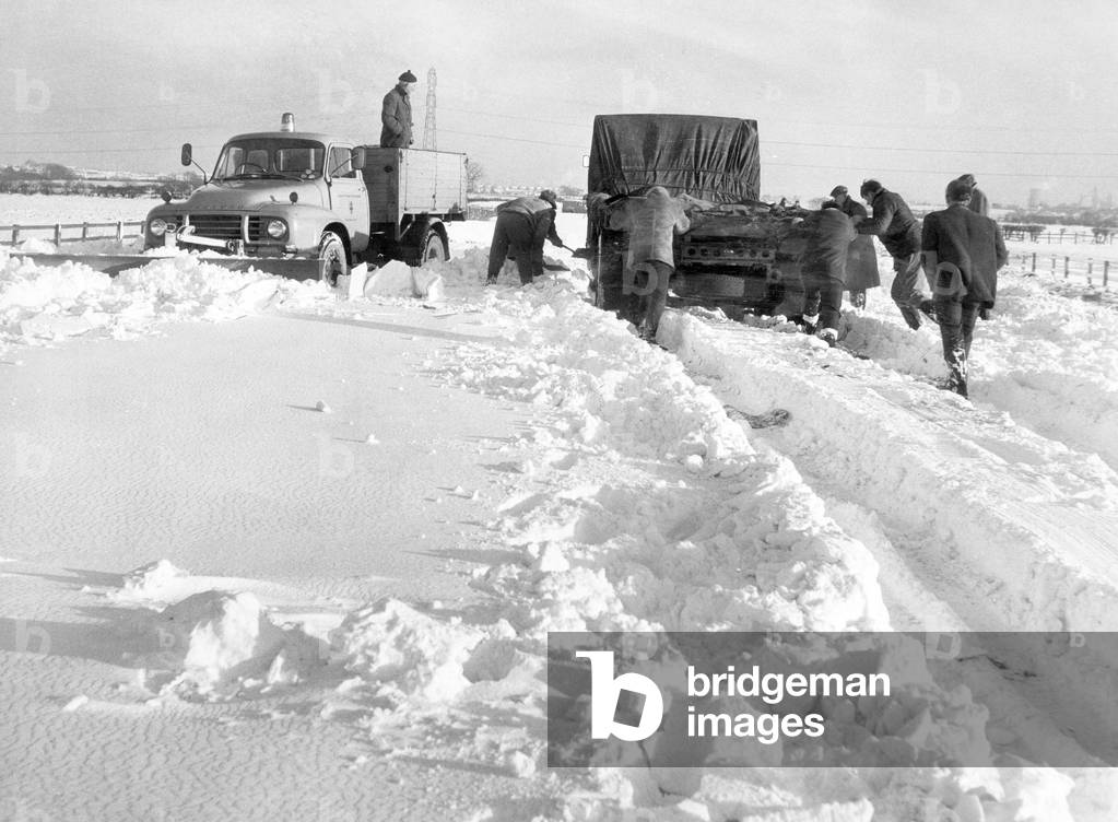 A combination of dig and push helps to free a lorry trapped on the Teesside to Hartlepool road, Middlesbrough. 28th December 1968 (b/w photo)