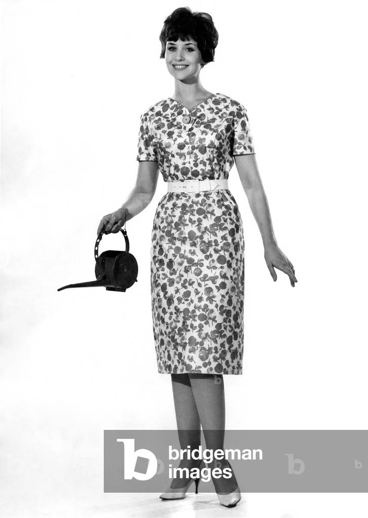 Reveille Fashions, Ann Cave wearing floral summer dress and holding a watering can, 8th June 1961 (b/w photo)