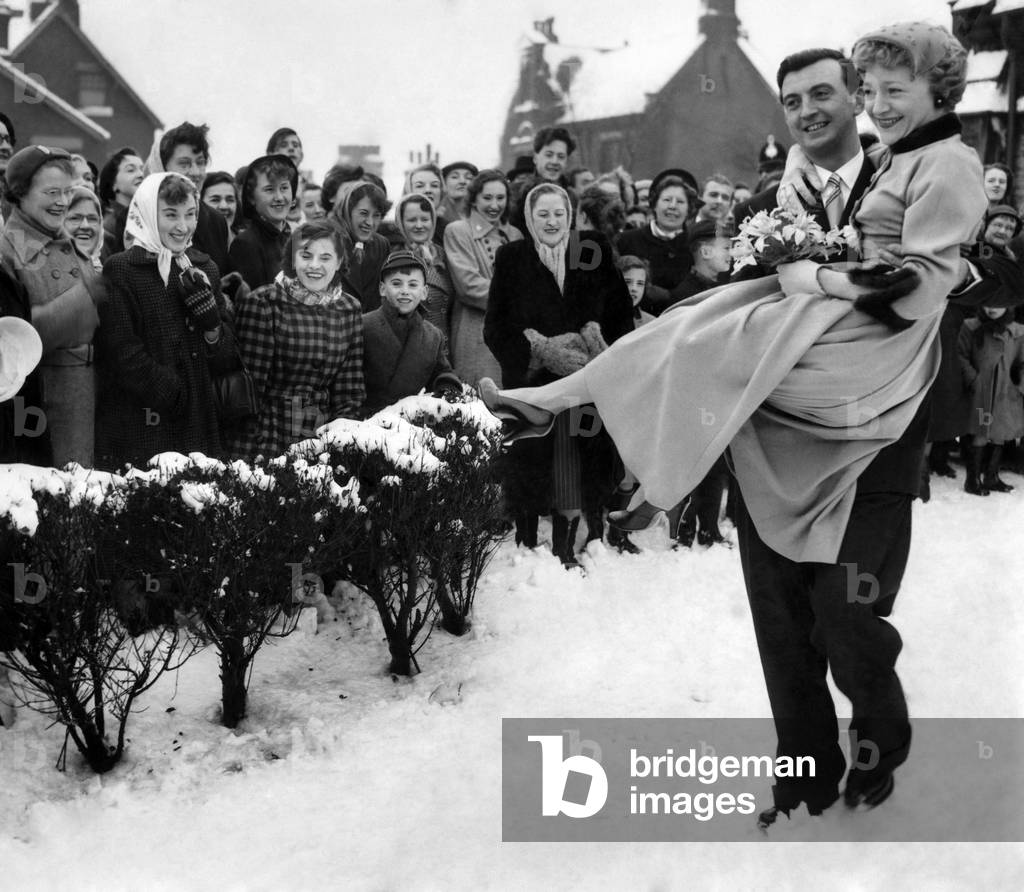 Dora Bryan, stage and film actress, seen here on her wedding day to Bill Lawton, a professional cricketer. As he carried her over the snow from St. Thomas's, Werneth, Oldham, Lancs, someone among the 600 people waiting outside shouted, 