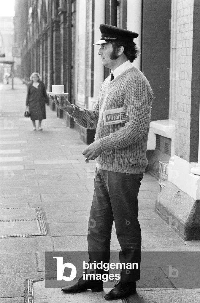 A day in the life of Jimmy Saville' Feature by Mike Hellicar. Dennis Garbutt, Savile's valet an driver, taking Jim's early morning cup of tea and newspaper across the road at Kings Cross to the motor home, 7th October 1971 (b/w photo)